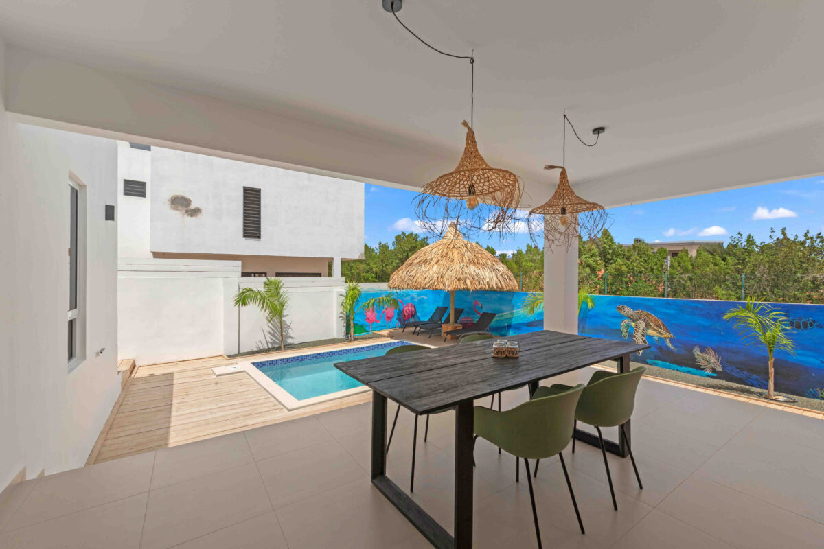Covered terrace with dining table overlooking private pool in Curaçao holiday villa